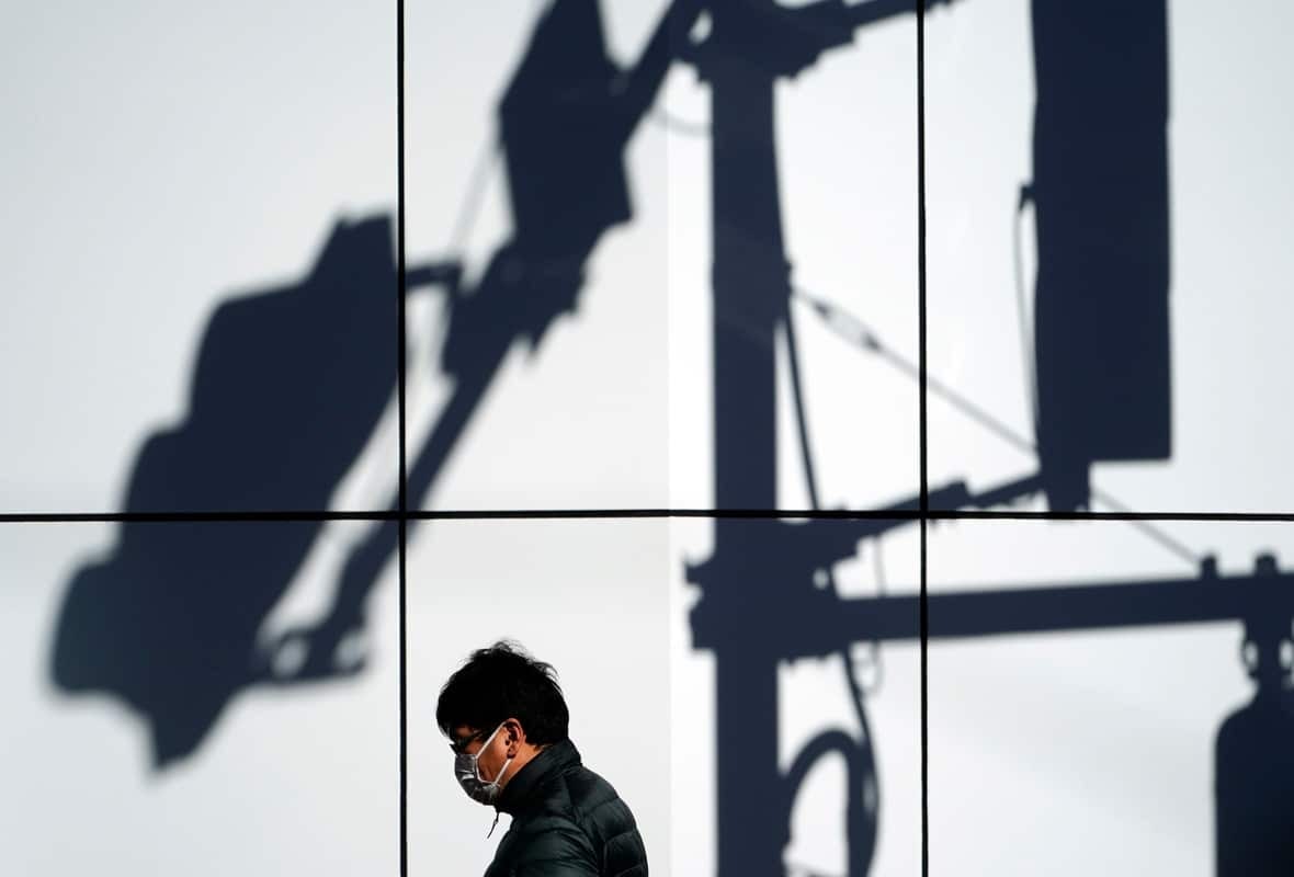 Photo of a man walking in shadow of surveillance cameras.
